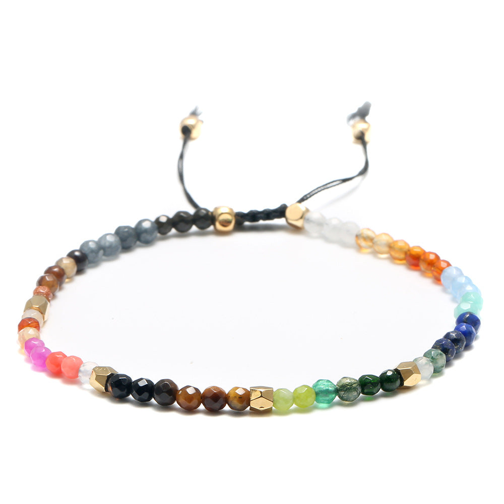 7 chakra bracelet shown flat with faceted multicolor agate beads, gold-tone spacers, and black braided adjustable cord with beaded tails against a white background for a full view.