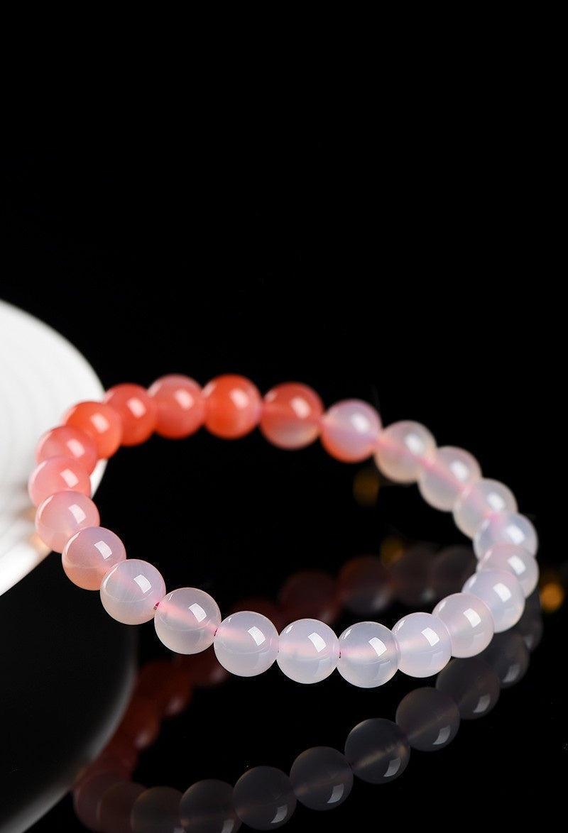 Two beaded bracelets on a reflective surface with 'Source' branding.