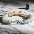 Amazonite gemstone bracelet with polished beads and silver charm styled on luxury marble surface.