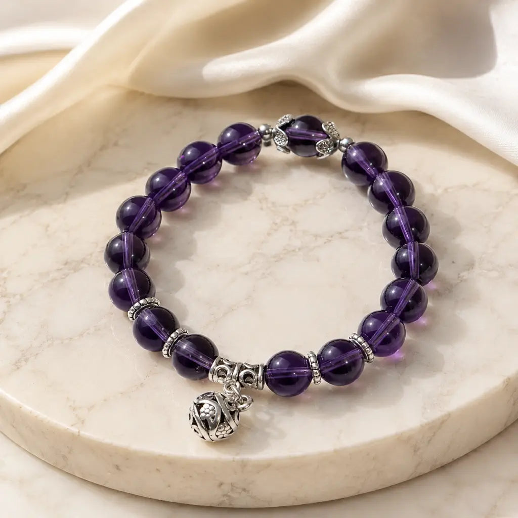 Violet Serenity amethyst bracelet on natural linen with glossy purple beads, showing genuine amethyst color variation, polished stone texture, and a simple everyday bracelet style.