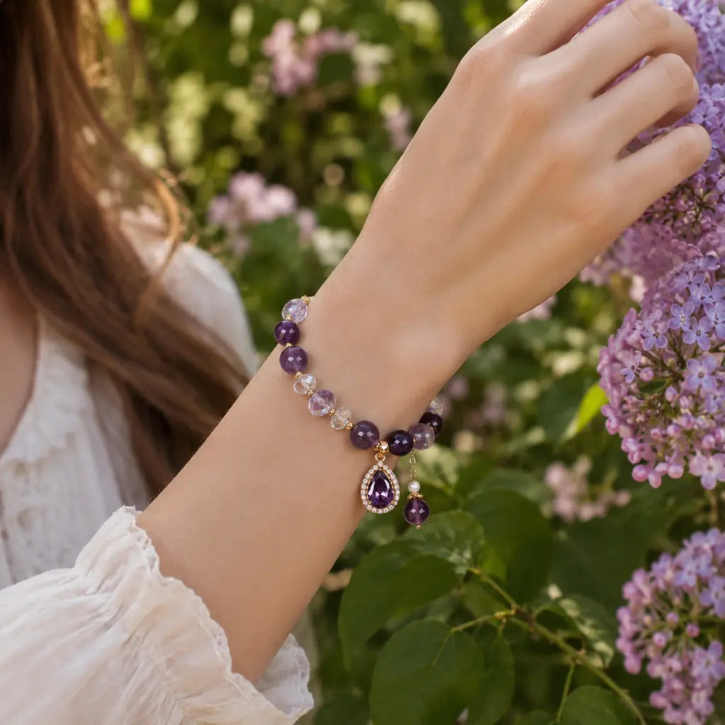 Amethyst crystal bracelet worn beside blooming flowers with healing gemstone beads for graceful beauty