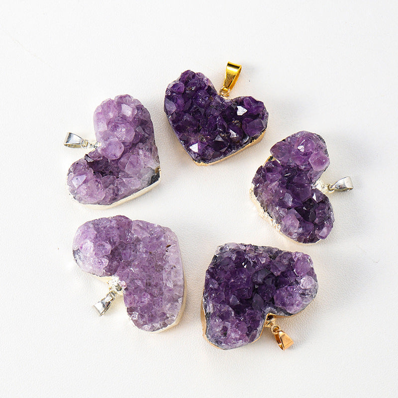 Amethyst heart pendant group with pale to deep purple crystal points irregular cluster texture, heart silhouettes, and mixed gold- and silver-color edging on a clean white display.