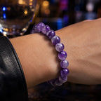 Amethyst jewelry glowing crystal bead bracelet worn at nightclub with vibrant purple gemstones and luxury party fashion appeal