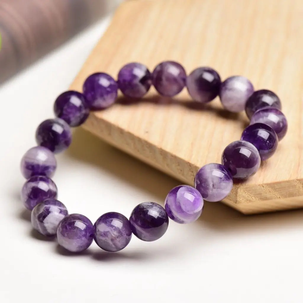 Amethyst jewelry handcrafted purple crystal bracelet displayed on wooden stand with elegant gemstone bead craftsmanship