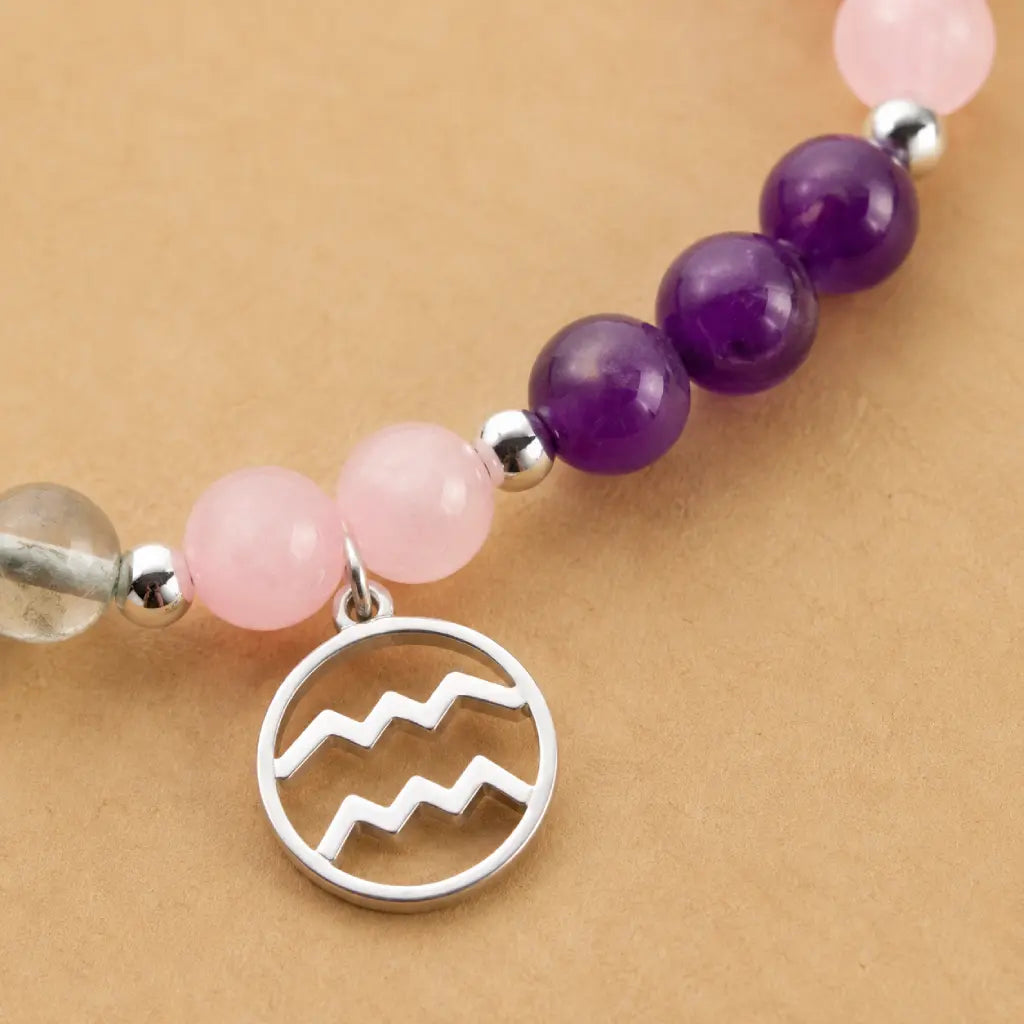 Aquarius stone bracelet closeup featuring silver zodiac pendant with rose quartz and amethyst healing crystal beads.