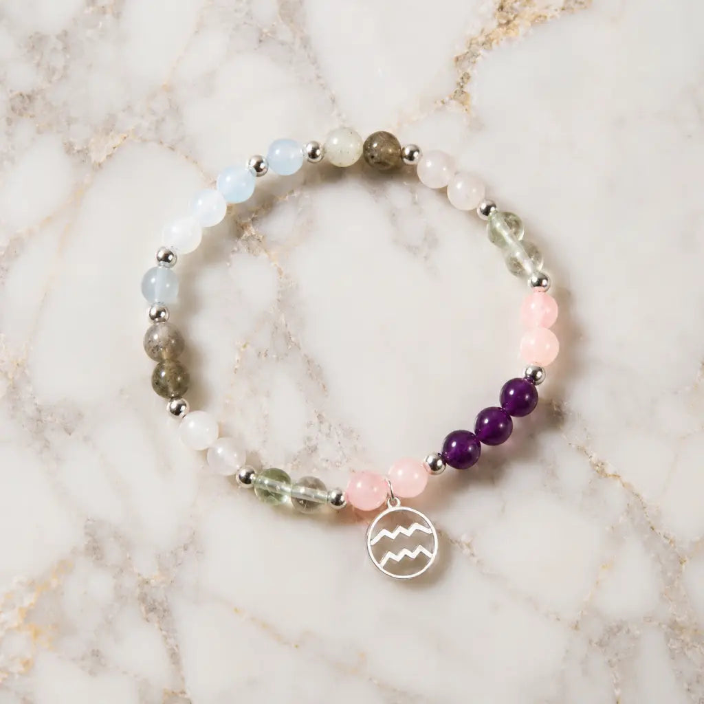 Aquarius stone bracelet featuring amethyst and rose quartz beads displayed on marble for chakra harmony styling.