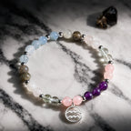 Aquarius stone bracelet displayed on dark marble with crystal beads and silver charm for mystical zodiac energy.