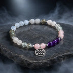 Aquarius stone bracelet with amethyst and rose quartz beads displayed on dark slate for mystical healing energy.