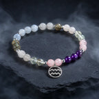 Aquarius stone bracelet styled on textured stone platform with crystal gemstones for luxury astrology inspired fashion.