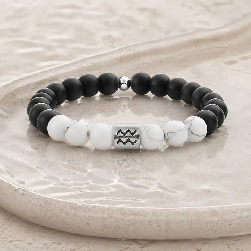 Aquarius zodiac bracelet on beige stone tray with black onyx, white howlite, and silver bead for elevated gifting