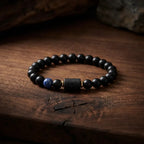 Aries zodiac bracelet on rustic wood with matte black beads, blue gem accent, and earthy premium gifting style