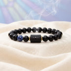 Aries zodiac bracelet on soft white fabric with black beads, blue stone accent, and calm healing style appeal now