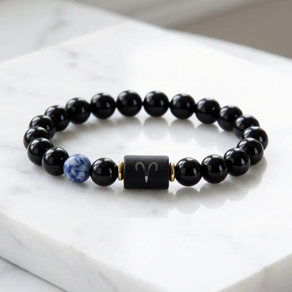 Aries zodiac bracelet on white marble with black beads, blue gem accent, and sleek modern gifting style appeal