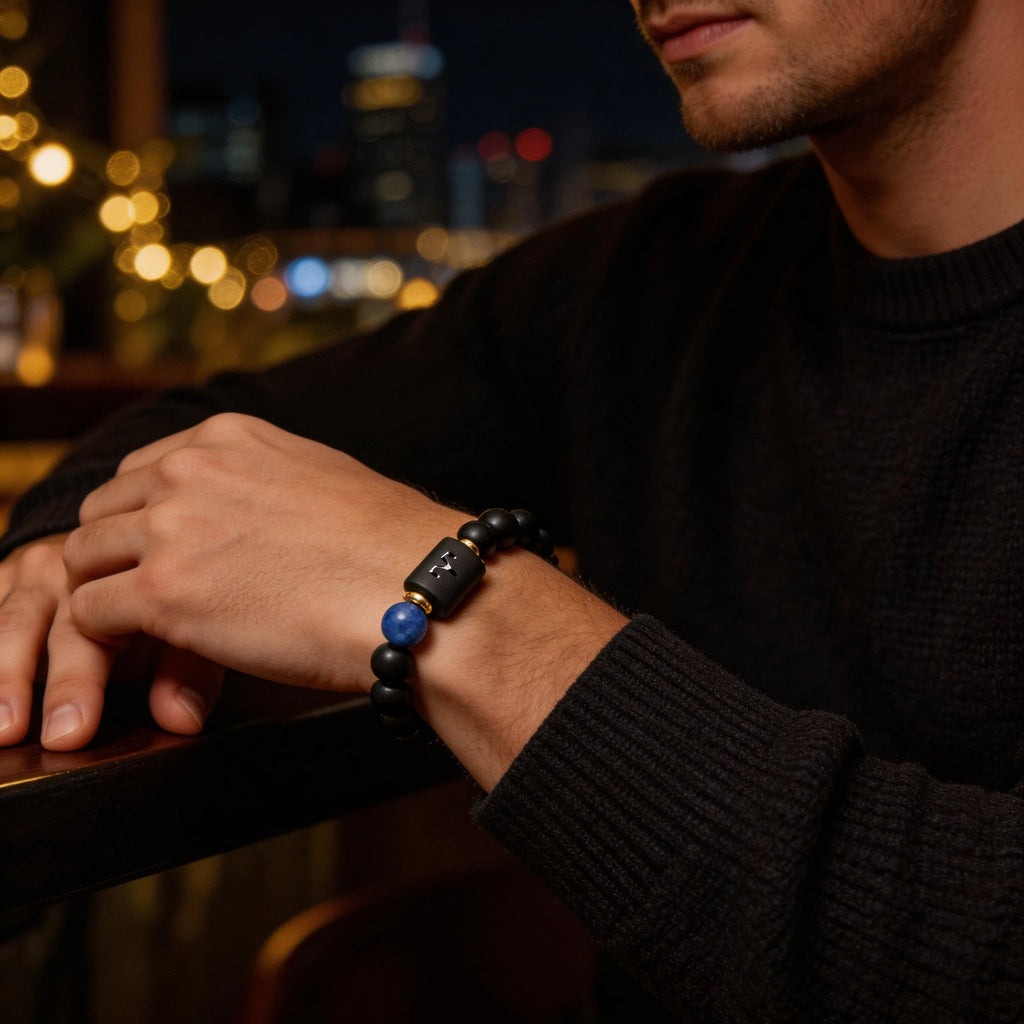Aries zodiac bracelet worn by a man with black bead design and blue stone accent for confident evening style