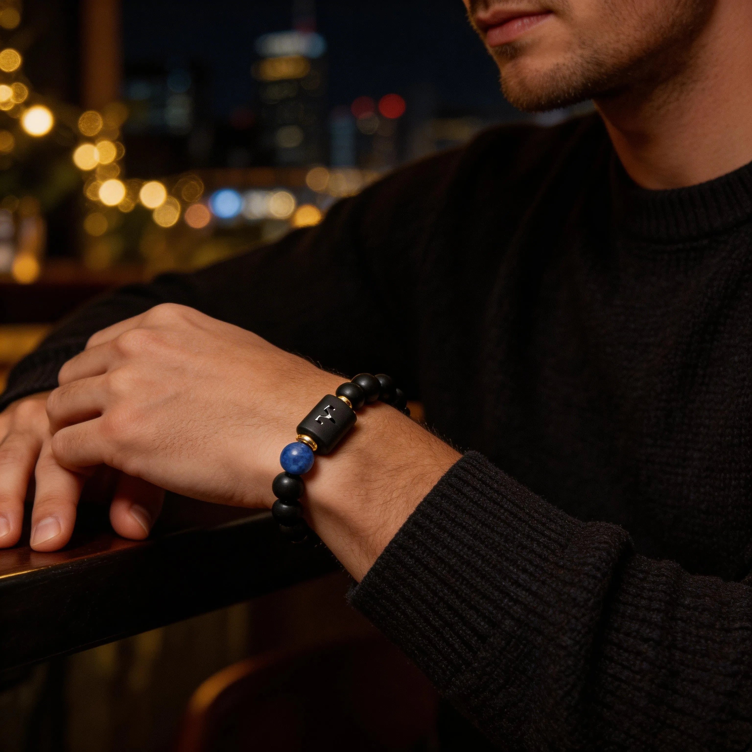 Aries zodiac bracelet worn by a man with black bead design and blue stone accent for confident evening style