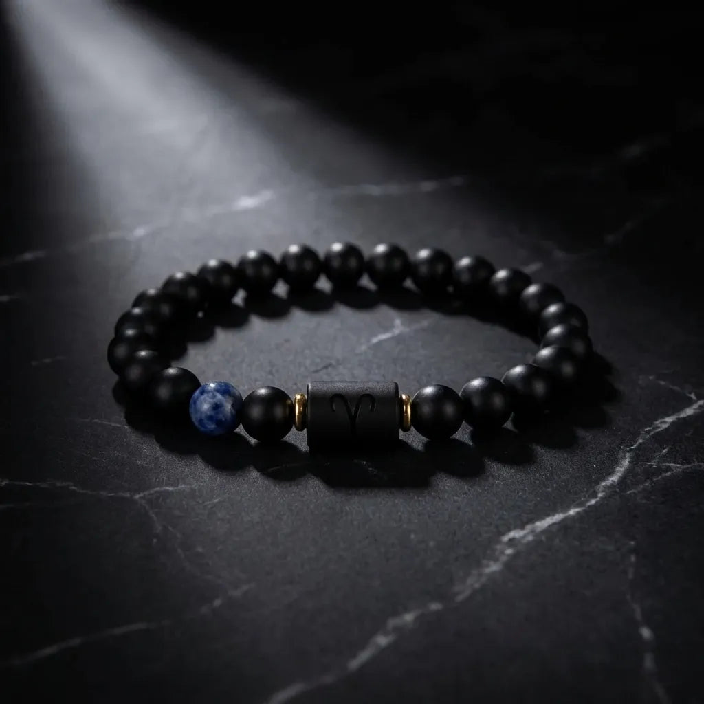 Aries zodiac bracelet on black marble with blue gemstone accent, matte beads, and dramatic luxury focus appeal