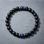 Matte black onyx bracelet with dual lapis lazuli blue beads laid flat on dark grey slate, best natural crystal gemstone bracelet 2026