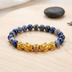 Blue tiger eye bracelet with blue stone beads, gold dragon charms, and wood display for lucky protection gift idea