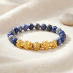 Blue tiger eye bracelet on soft linen with blue gray gemstone beads and gold dragon charms for calm confidence