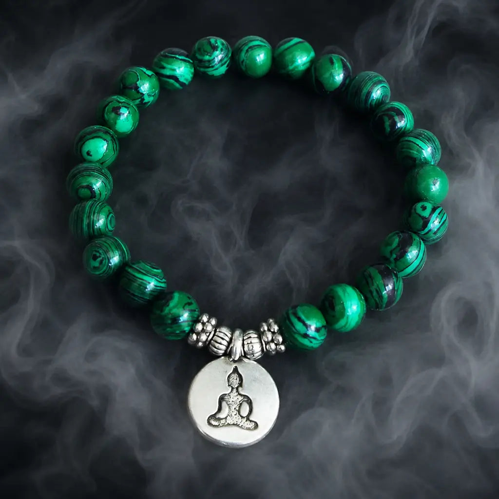 Buddha green tigereye beaded bracelet with silver charm and swirled malachite-style beads on dark background