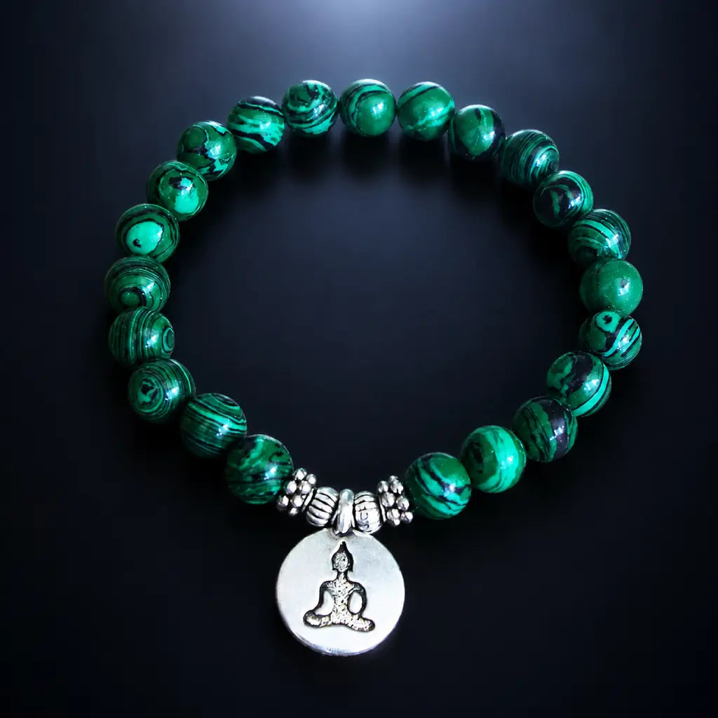 Buddha green tigereye healing stone bracelet with silver charm, deep green swirled beads on dark glowing surface