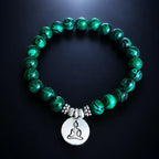 Buddha green tigereye healing stone bracelet with silver charm, deep green swirled beads on dark glowing surface