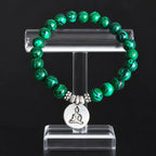 Buddha green tigereye bracelet displayed on acrylic stand, striped green beads with silver meditation Buddha charm