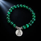 Buddha green tigereye bracelet glowing under spotlight with bold striped green beads and silver Buddha coin charm