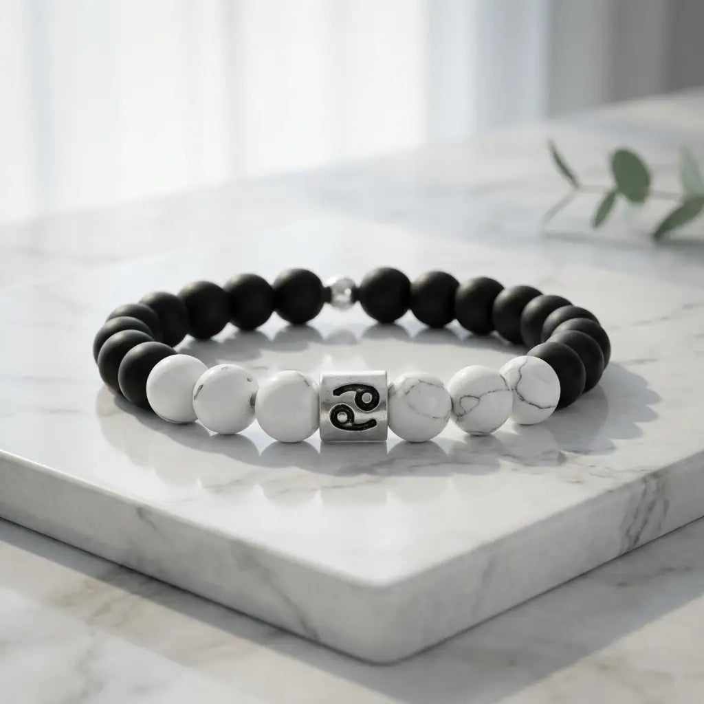 Black and white beaded bracelet with a silver charm on a marble surface
