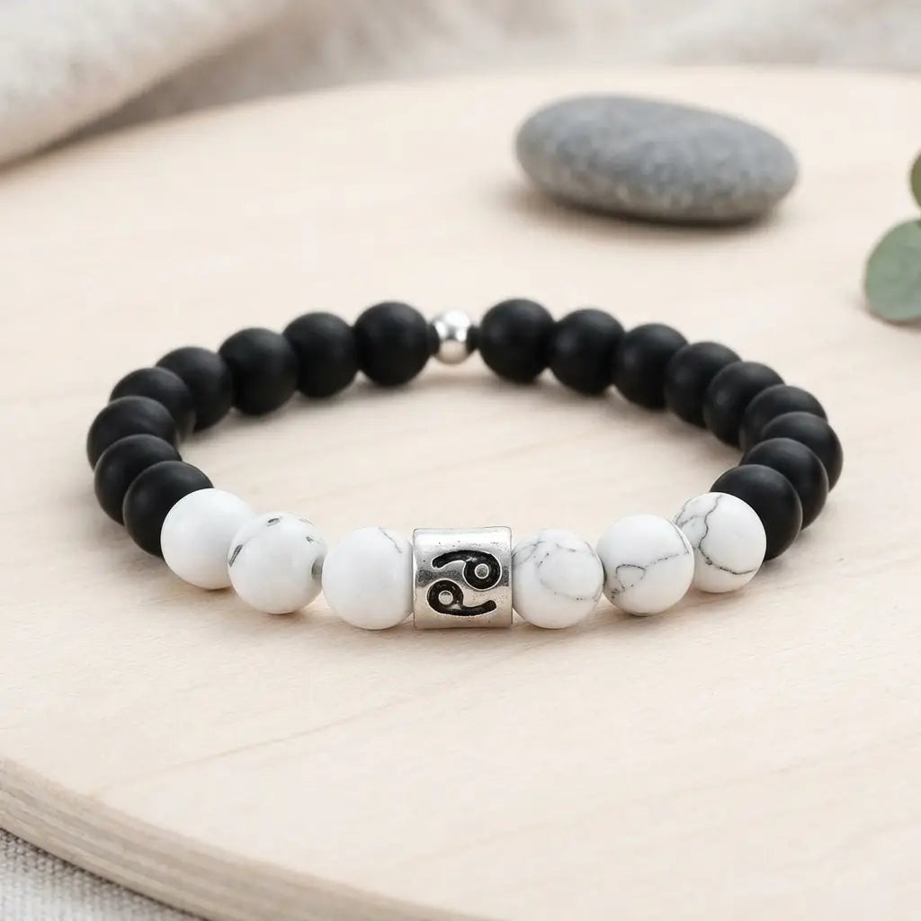 Black and white beaded bracelet with a silver charm on a wooden surface.