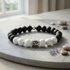 Black and white beaded bracelet on a stone surface with stones and a flower in the background