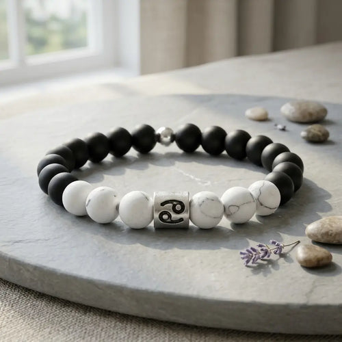 Black and white beaded bracelet on a stone surface with stones and a flower in the background