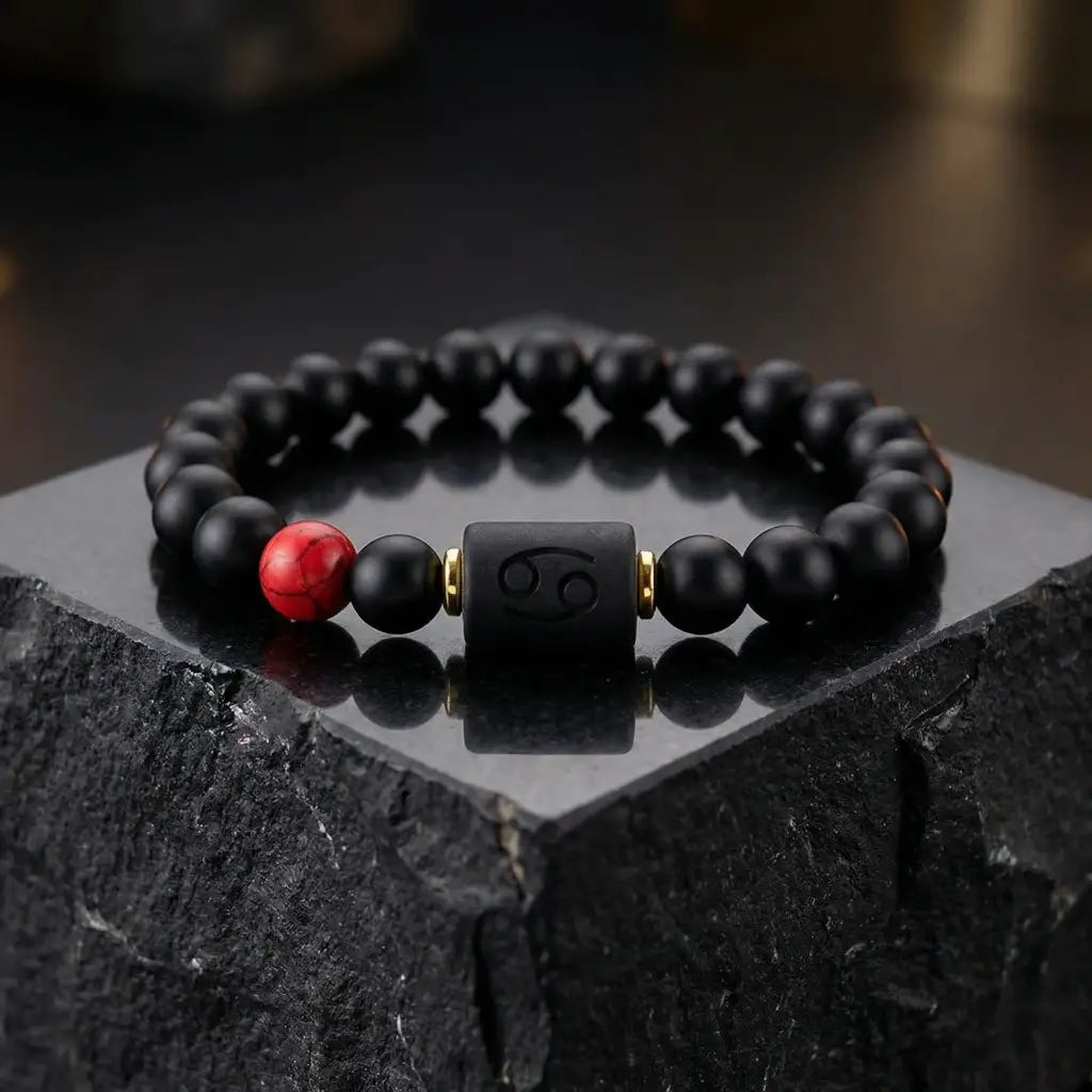 Cancer zodiac bracelet black beaded design with red stone displayed on dark stone platform emphasizing premium modern elegance jewelry