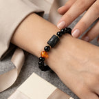 Capricorn zodiac bracelet on wrist near gift box with black beads and amber accent, perfect for thoughtful gifting moments