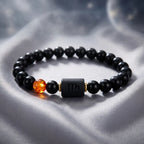 Capricorn zodiac bracelet on soft silver fabric with black beads and amber accent, offering elegant astrology jewelry styling