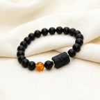 Capricorn zodiac bracelet on soft fabric with matte black beads and amber accent, offering elegant everyday jewelry style