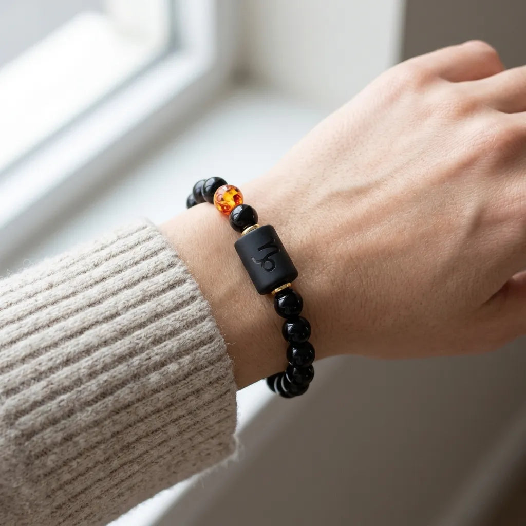 Capricorn zodiac bracelet styled with knit sleeve and amber bead, creating a cozy everyday fashion statement