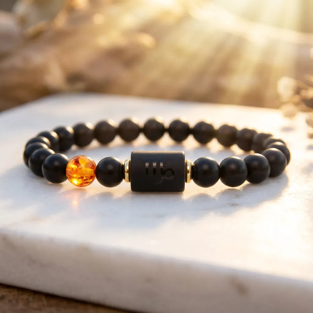 Capricorn zodiac bracelet with black beads and amber charm glowing in golden sunlight on marble, creating warm luxury appeal
