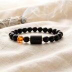 Capricorn zodiac bracelet on soft fabric with smoke background, black beads and amber charm evoke calm spiritual energy