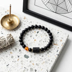 Capricorn zodiac bracelet displayed with incense and decor, black beads and amber detail create calming spiritual aesthetic