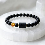 Capricorn zodiac bracelet displayed on white crystal base, black beads and amber accent emphasize clean modern jewelry design