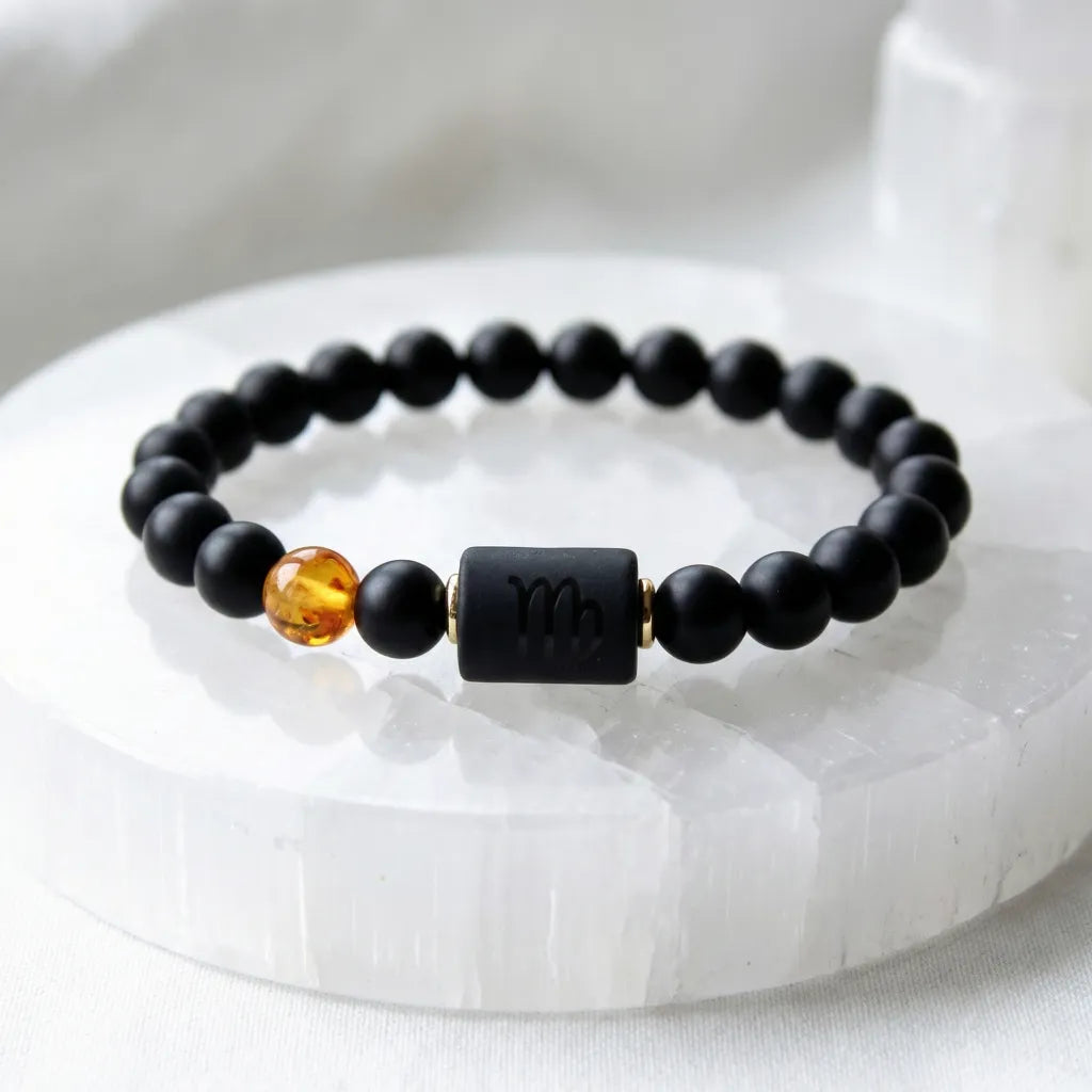 Capricorn zodiac bracelet displayed on white crystal base, black beads and amber accent emphasize clean modern jewelry design