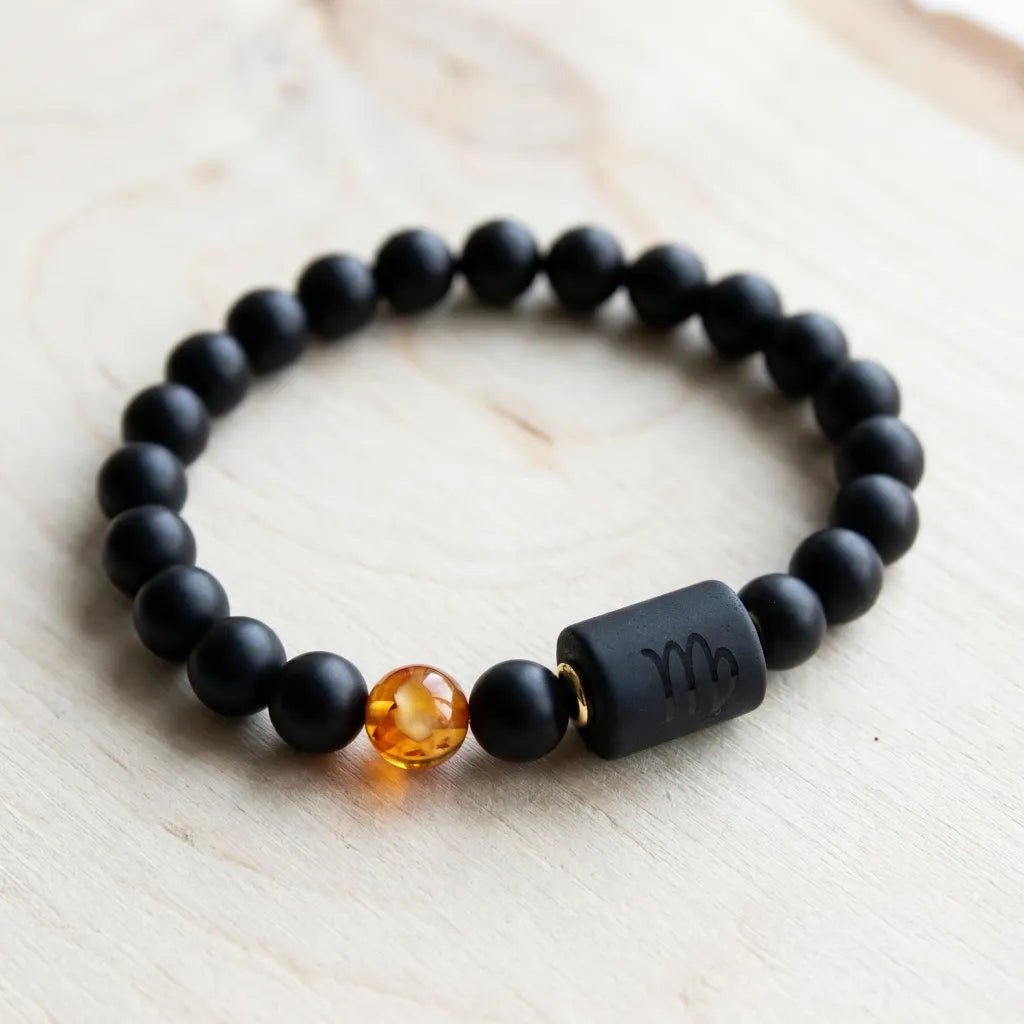 Capricorn zodiac bracelet flat lay with black matte beads and amber charm, highlighting premium craftsmanship and design