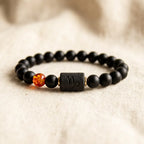 Capricorn zodiac bracelet with black lava beads and amber detail on neutral background, highlighting earthy modern aesthetics