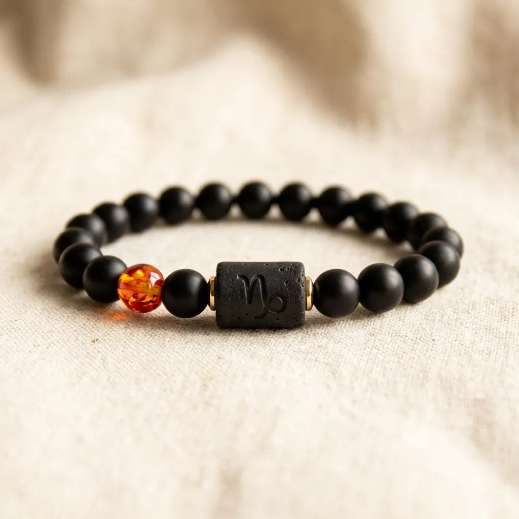 Capricorn zodiac bracelet with black lava beads and amber detail on neutral background, highlighting earthy modern aesthetics
