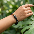 Capricorn zodiac bracelet displayed outdoors with matte black beads and amber detail for earthy, balanced style