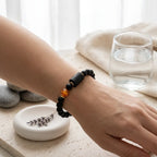 Capricorn zodiac bracelet beside spa elements with black beads and amber detail, promoting calm and mindful self-care ritual