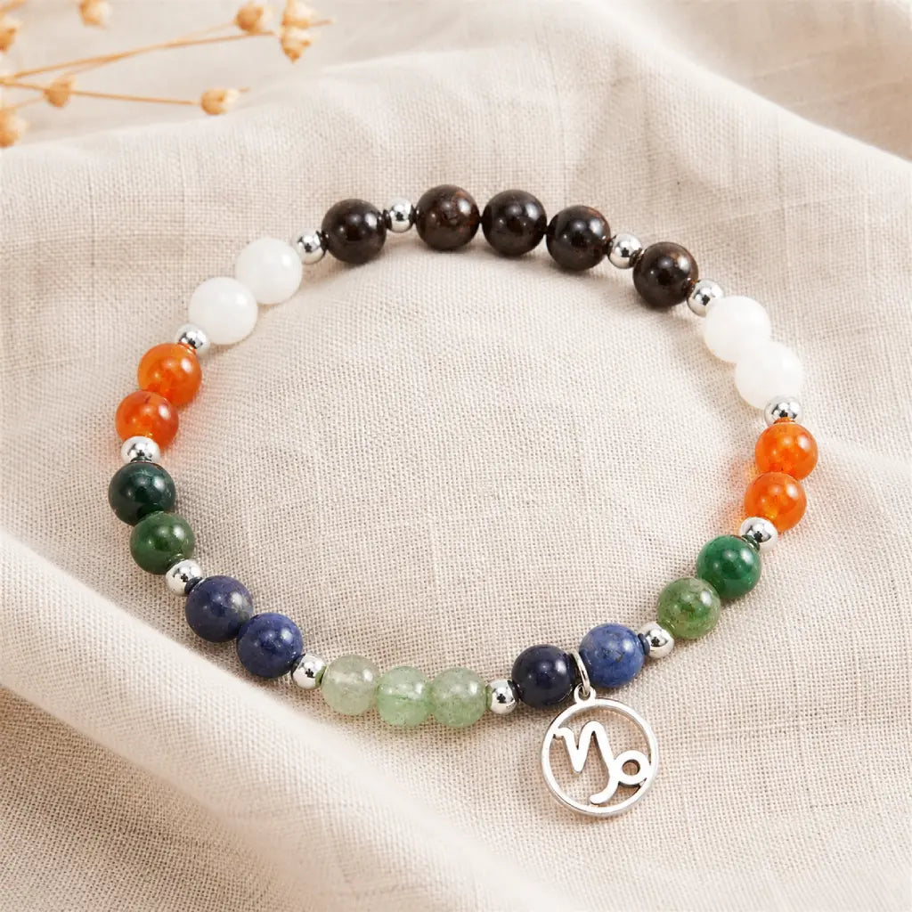 Capricorn zodiac crystal bracelet arranged on linen fabric highlighting natural gemstone colors and artisan craftsmanship.
