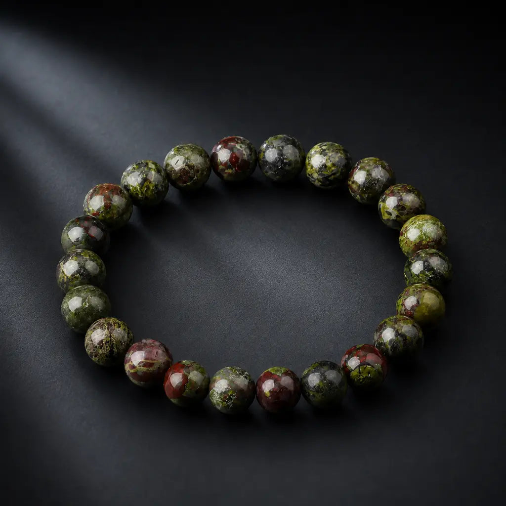 Dragon blood stone bracelet with diagonal spotlight on dark leather surface, vibrant green red jasper crystal bracelet