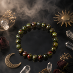 Dragon blood stone bracelet on dark surface with crystals, moon and sun charms, mystical healing jewelry flat lay